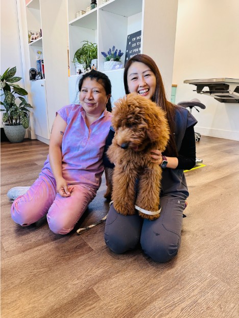 Dr. Chen holding a dog on her lap with a co-worker